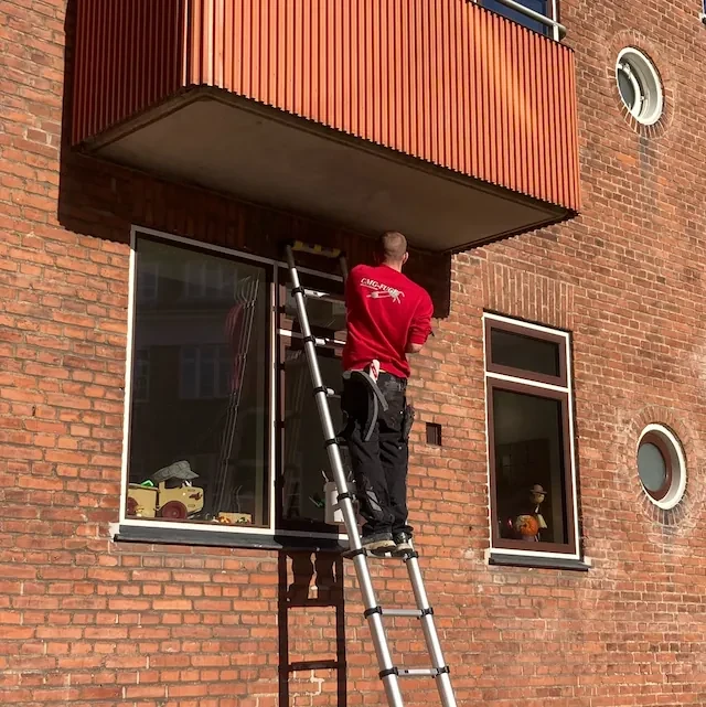 Fugemand udfører fugning omkring vinduer på facade i Hillerød, Nordsjælland.